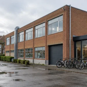 AI-illustration: Nordisk erhvervsejendom i tegl med cykler ved indgangen